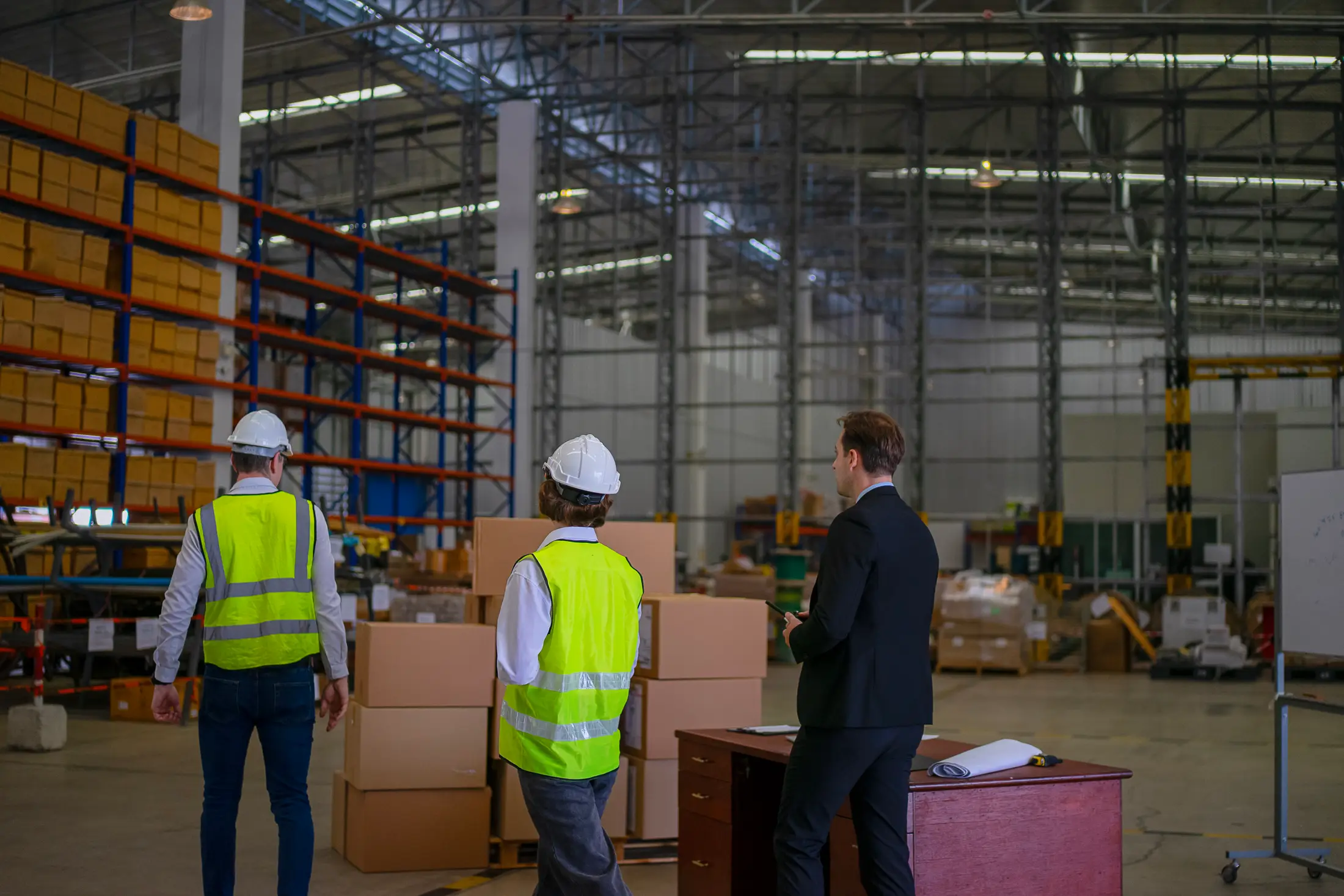 Warehouse supervisor reviewing work with two team members